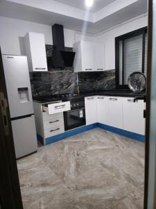 a kitchen with white cabinets and a tile floor at Luxury apartment in Ariana