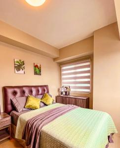 Un dormitorio con una cama con almohadas amarillas y una ventana. en One Bedroom Condominium Avida Tower 1 Aspira CDO, en Cagayan de Oro