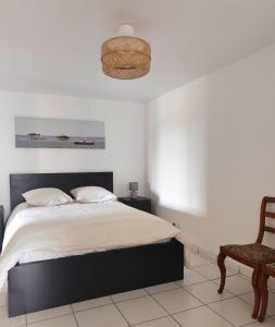 ein weißes Schlafzimmer mit einem Bett und einem Stuhl in der Unterkunft La maison de l'Architecte - Gite proche Bordeaux in Salleboeuf