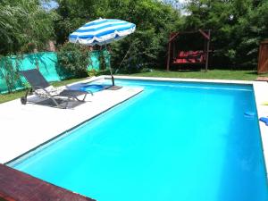 a swimming pool with an umbrella and a chair at Liguria in San Geronimo