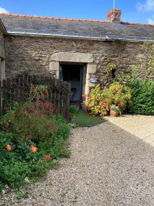 a stone house with a doorway and flowers in front of it at Gîte la peille in Cordemais
