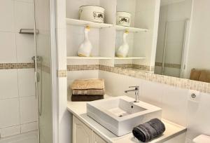 a white bathroom with a sink and a mirror at Maison Les aloes - vue mer et proche centre ville in Propriano +18 photos
