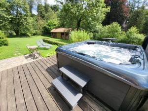 a hot tub sitting on a wooden deck with stairs at B&B Le Bois de Champia in Huy