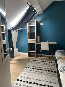 a bedroom with a blue wall with a bed and a desk at Petite pause au calme dans la ville in Aulnoy