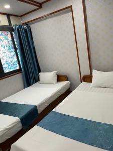 ハノイにあるAsia Cozy Houseの窓のある小さな部屋にベッドが2つある