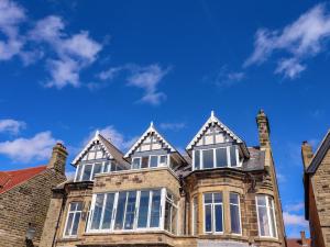 a large brick house with windows and a blue sky at Ocean View in Alnwick