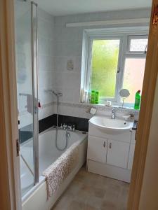 a bathroom with a shower and a tub and a sink at Family home in Poole