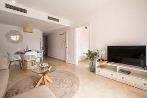 salon z dużym telewizorem i stołem w obiekcie Aquamarine apartment in Marina Sotogrande w mieście Sotogrande