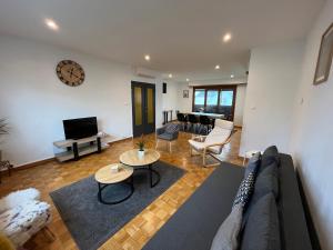 Una sala de estar con un sofá, una mesa y un televisor. en Appartement de 115m2 à 10 min de Strasbourg & 25 min d'Europa Park !, en Illkirch-Graffenstaden