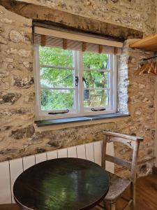 a table and chair in a room with a window at The Drewe Arms, Broadhembury in Broadhembury +2 photos