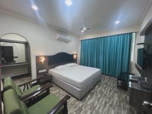 a bedroom with a bed and two chairs and a television at Varada nagavali hotel in Srīkākulam