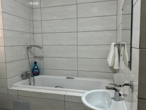 a white bathroom with a tub and a sink at SiaMo Suite in Gaborone +14 photos