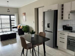 a kitchen and a living room with a table and chairs at SiaMo Suite in Gaborone