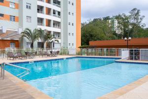 a large swimming pool in front of a building at Apto a 10 min da Vila Germânica, dois quartos, salas de estar e jantar, cozinha completa, sacada com churrasqueira, Wi-Fi, Piscina, academia, mercadinho 24 horas e Vaga de garagem in Blumenau
