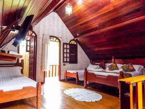 Un dormitorio con dos camas y techo de madera. en Pousada Monjolos de Minas a 9 km de Gonçalves, en Gonçalves