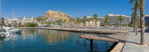 a marina with a bench in the water with buildings at Melia Alicante in Alicante