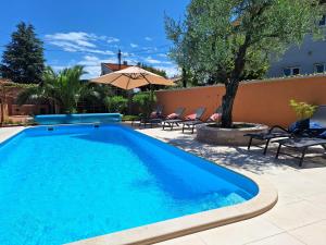 a swimming pool with chairs and an umbrella at Paradise for children, Family apartment Oros Medulin, with a pool, gd in Medulin +17 photos