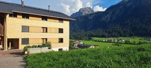a building on a hill with mountains in the background at Ferienwohnung BergTraum in Schoppernau