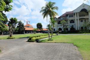 a building with a palm tree in front of it at Hotel Dhyana Pura in Kapal