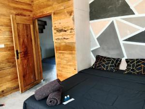 比哈尔Anggie Homestay的一间卧室配有一张黑色床和木墙