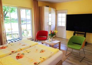 a bedroom with a bed and two chairs and a tv at Hotel Haus Orchideental Jena in Jena