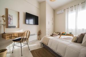 a bedroom with a bed and a chair and a tv at Aquamarine - Beach Flat in Itea