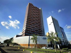 a tall building next to a building with palm trees at Flat Manaus Hotéis Millenium in Manaus