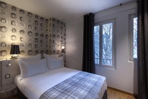 a bedroom with a bed and a wall with plates at Le Mireille in Paris