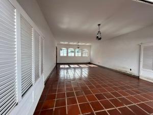 an empty room with white walls and a red tile floor at Pousada Casa da Vó Dita in Ouro Fino