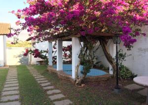 a gazebo with purple flowers and a tree at Pousada Casa da Vó Dita in Ouro Fino