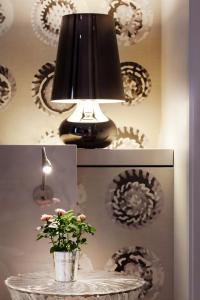 a table with a lamp and a vase with a plant at Le Mireille in Paris