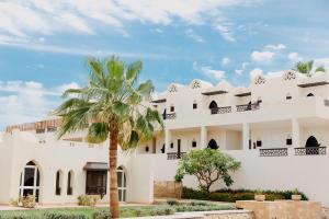 a building with a palm tree in front of it at Reef Oasis Beach Aqua Park Resort in Sharm El Sheikh