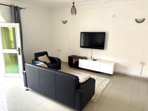 a living room with two chairs and a flat screen tv at Appartements modernes, Wifi, TV - Yaoundé, Omnisports in Yaoundé
