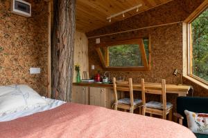 a bedroom with a bed and a kitchen with a table at La sat - Ană Năzdrăvană in Bertea