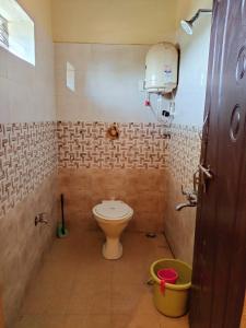 a bathroom with a toilet and a bucket in it at Namitha guest house in Hampi