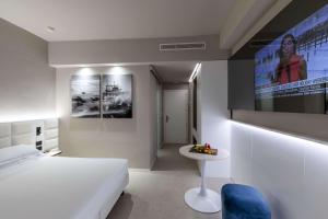 a bedroom with a white bed and a tv on the wall at Hotel Cristallo in Giulianova