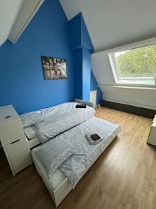 a blue bedroom with a bed and a window at Maison familiale et cosy in Argenteuil