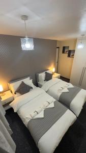 a hotel room with two beds and two lamps at Grand House in Dagenham