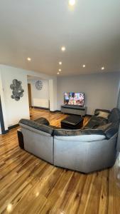 a large couch in a living room with a flat screen tv at Grand House in Dagenham