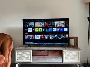 a flat screen tv sitting on top of a tv stand at The Phantom Apartment 1 minute walk to JR, Churchill Manor Nuffield Hospitals Oxford B Uni, Sleeps 5 Guests comfortably very modern 2 rooms 3 bathrooms Private Garden in Oxford