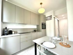 a kitchen with white cabinets and a table with wine glasses at Le City, Centre-ville, Climatisation, Trams in Grenoble