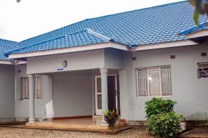 a white house with a blue roof at Kimi's Place Lodge in Mzuzu
