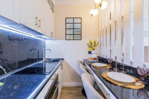 a kitchen with black counter tops and white cabinets at Новая дизайнерская квартира в Соломенском районе Киева in Kyiv +37 photos
