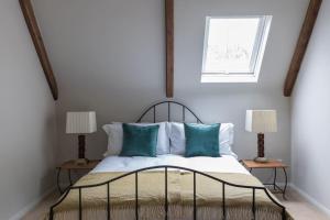 a bedroom with a bed with blue pillows and a window at The Loft in Faygate