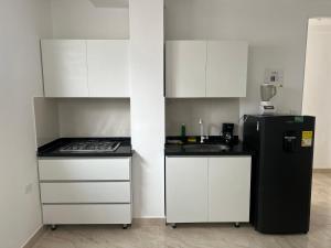 a kitchen with white cabinets and a black refrigerator at Apartamento en el Centro de Pitalito in Pitalito