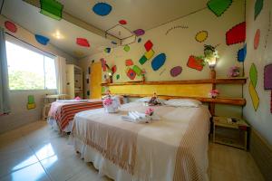 two beds in a room with a wall covered in kites at Pousada das Galinhas in Porto De Galinhas