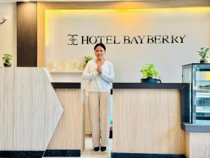 a woman standing behind a counter in a hotel lobby at Hotel Bayberry Kathmandu - Near Tribhuvan International Airport in Kathmandu