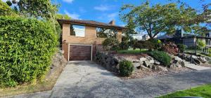 a brick house with a garage and a driveway at HomeSmart: Cozy Charm Meets High-Tech in Prime Area in Seattle