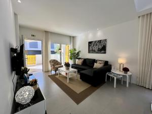 un salon avec un canapé noir et une table dans l'établissement Vilamoura Club Villa 1 With Pool by Homing, à Vilamoura