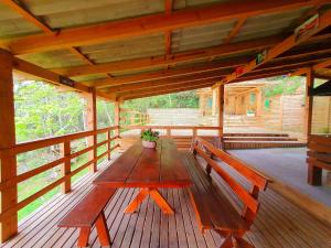 Una mesa de madera en un porche con un banco. en Casa dos Alpes com Jacuzzi hidro e Lareira, en Santo Amaro da Imperatriz